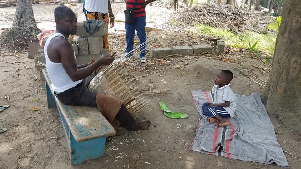 Man basket-weaving in front of amazed child, African Travel